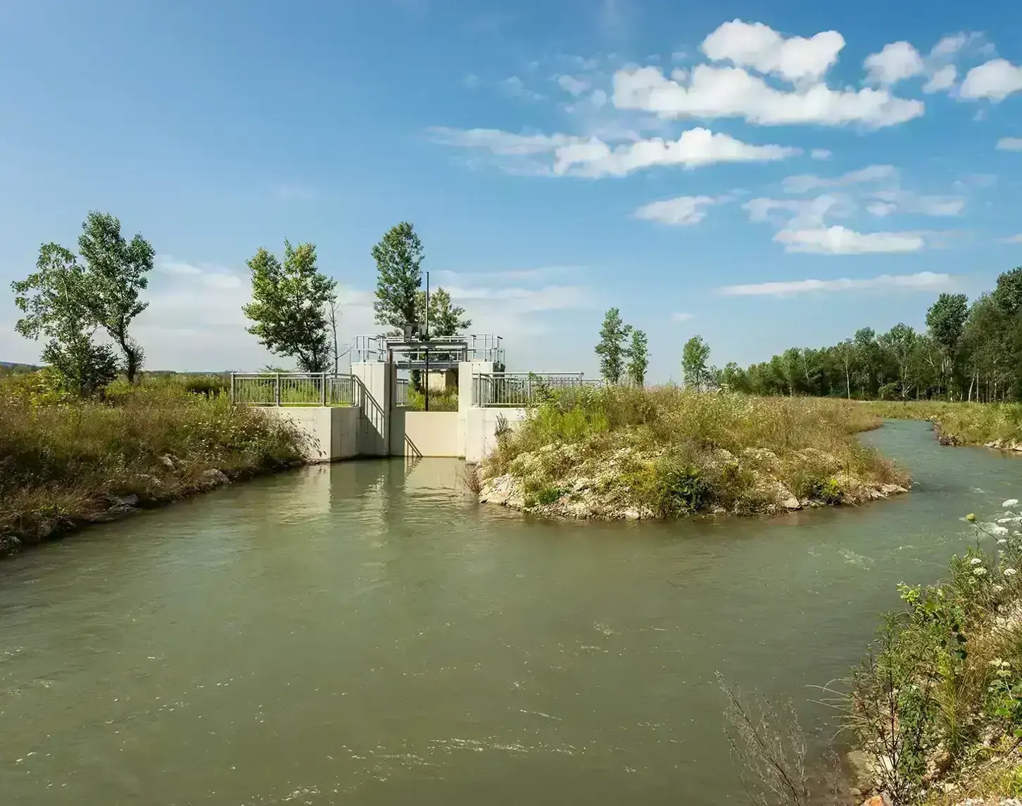 The fish migration aid near Greifenstein blends in well with nature. The sky is bright blue and the bank is already overgrown.